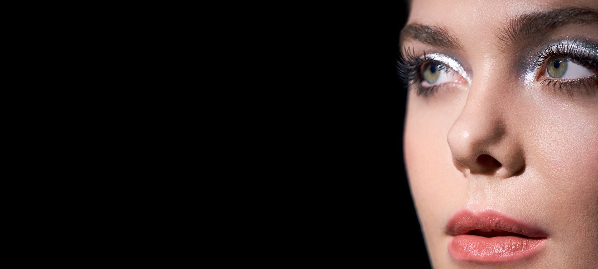  Eine junge Frau mit Smokey Eyes Make-up vor schwarzem Hintergrund