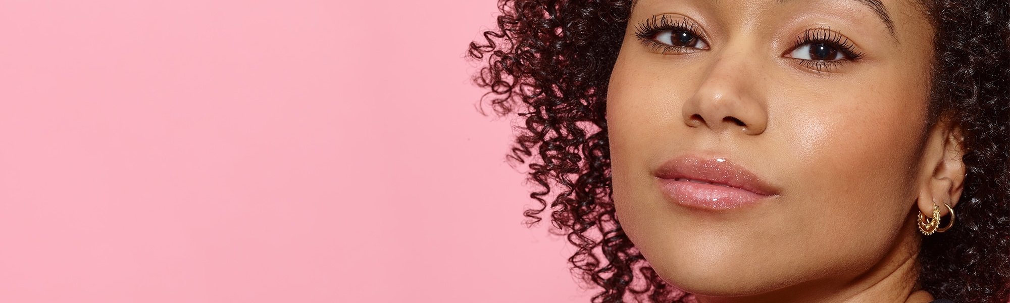 Eine junge Frau mit lockigen Haaren und dezentem Make-up
