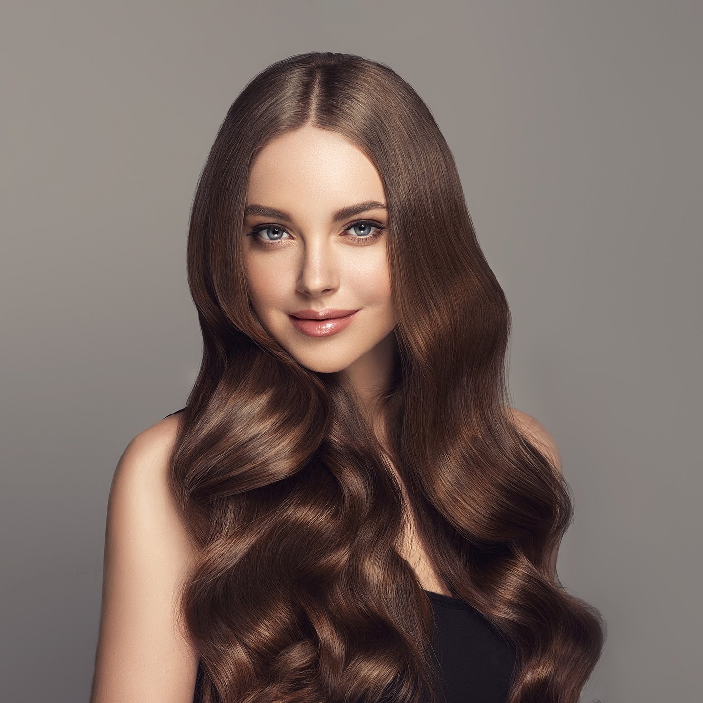 Bruenettes Model mit gepflegtem welligem Haar schaut in die Kamera