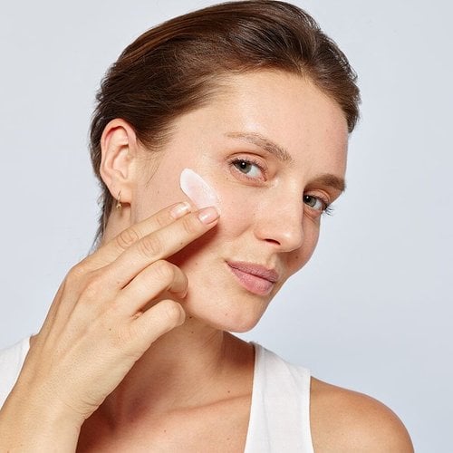 Frau trägt Creme auf die Wange auf