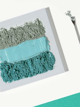 Verschiedenfarbige Tonerden ordentlich nebeneinander gereiht, daneben zwei Laborspachtel