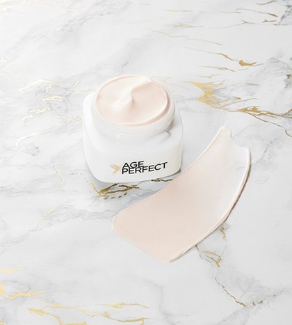 geoeffneter Tiegel der Age Perfect Pro Kollagen Experte Tagespflege mit Cremeklecks auf Marmor