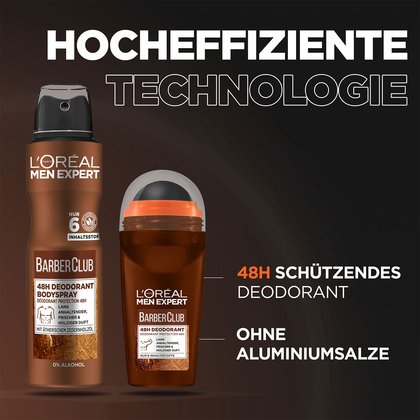 Eine Hand haelt das Barber Club Bartoel vor roter Steinmauer