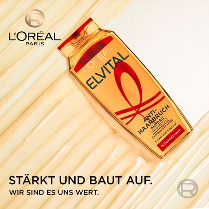 Schräg liegende Elvital Anti-Haarbruch Shampoo-Flasche auf einer cremigen Produkttextur mit dem Logo von L'Oréal Paris und dem Slogan „Stärkt und baut auf. Wir sind es uns wert.“