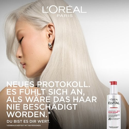 Werbebild mit dem Profil einer Frau mit seidigem, platinblondem Haar auf der linken Seite. Rechts unten steht die Flasche des Bond Repair Leave-In Serums. Der Slogan lautet: „NEUES PROTOKOLL. ES FÜHLT SICH AN, ALS WÄRE DAS HAAR NIE BESCHÄDIGT WORDEN.* DU BIST ES DIR WERT.“ mit der Fußnote „*Verbrauchertest mit 168 Personen“.