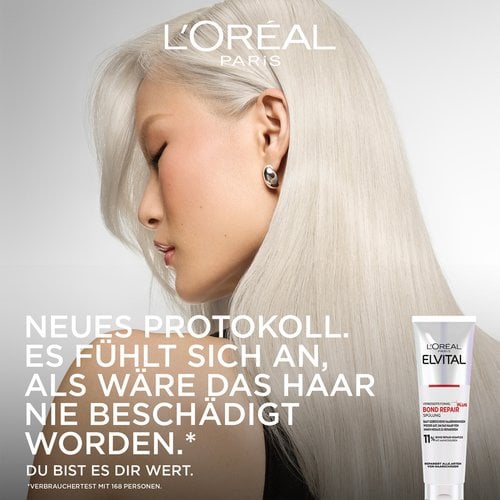 Werbebild mit dem Profil einer Frau mit seidigem, platinblondem Haar auf der linken Seite. Rechts unten ist die Tube der Bond Repair Spülung abgebildet. Der Slogan lautet: „NEUES PROTOKOLL. ES FÜHLT SICH AN, ALS WÄRE DAS HAAR NIE BESCHÄDIGT WORDEN.* DU BIST ES DIR WERT.“ mit der Fußnote „*Verbrauchertest mit 168 Personen“.