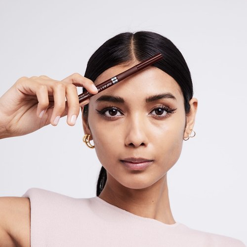 Brünette Frau hält Infaillible Eyeliner Infaillible 27h Grip Precision Felt Liner 02 braun Produkt vor ihre Stirn