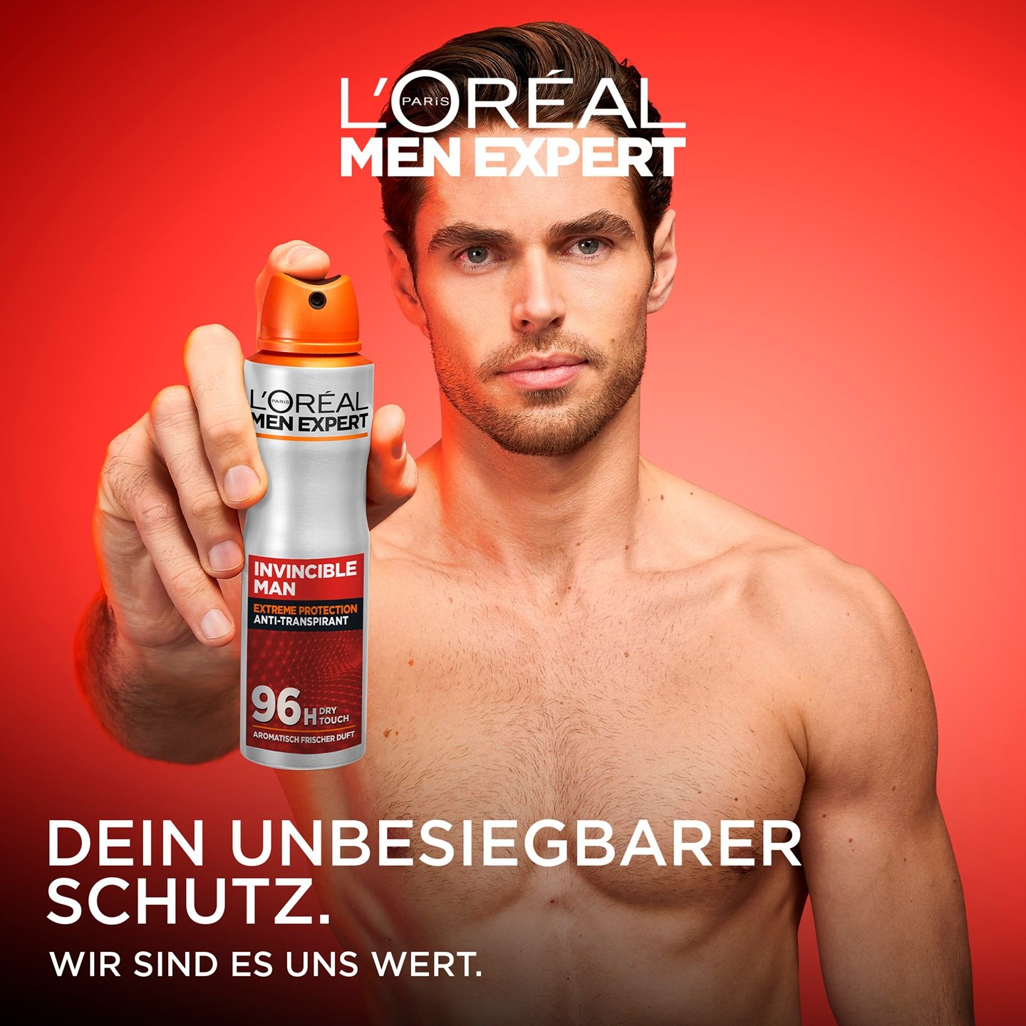 Ein Mann hält das Invincible Man Deospray vor rotem Hintergrund direkt in die Kamera.