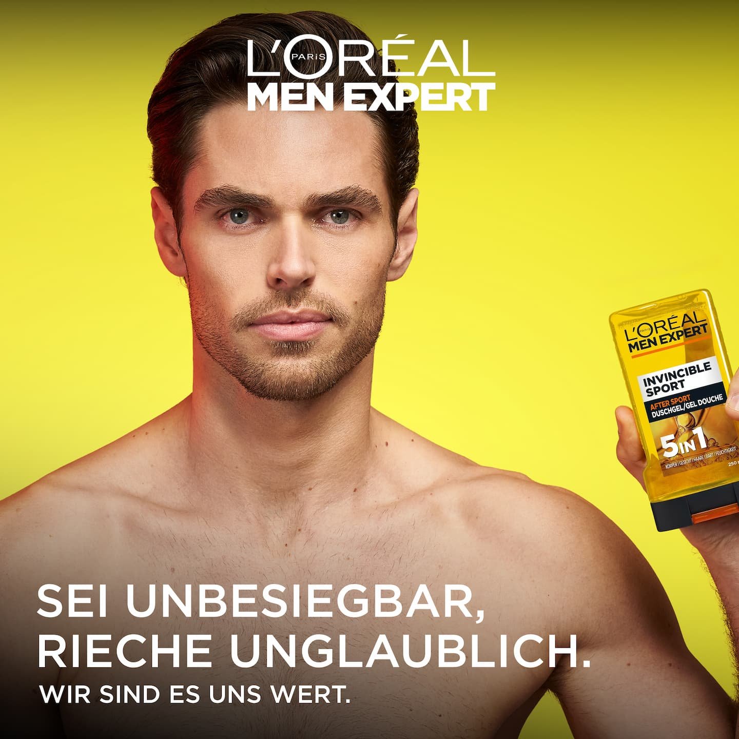 Ein Mann hält das gelbe Invincible Sport Duschgel neben sein Gesicht.