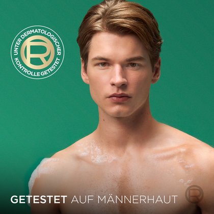Porträt eines Mannes mit nasser Haut und dezentem Schaum auf den Schultern vor grünem Hintergrund unter dem runden Siegel „UNTER DERMATOLOGISCHER KONTROLLE GETESTET“