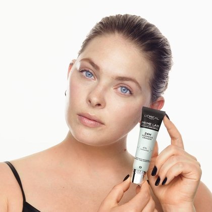 Eine Frau hält Prime Lab 24h Redness Eraser Produkt in ihrer Hand