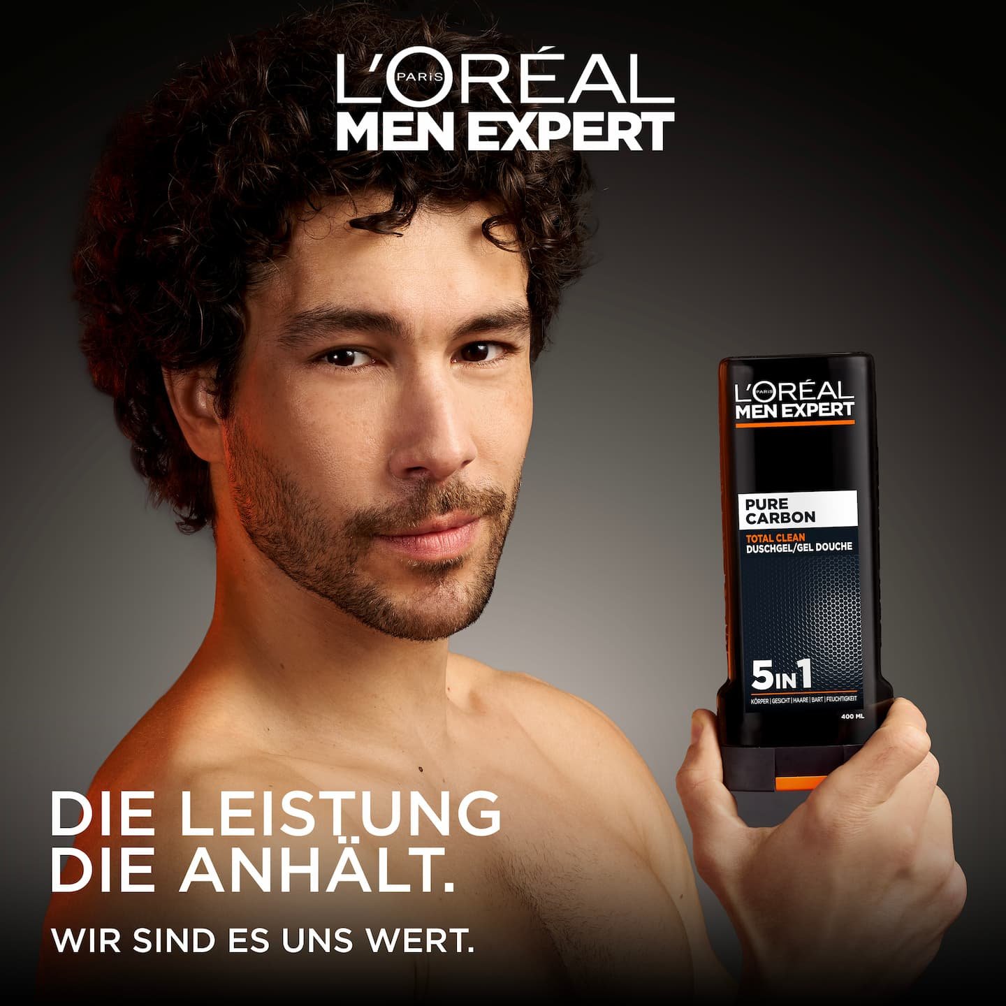 Ein Mann hält das Pure Carbon 400ml Duschgel vor grauem Hintergrund.
