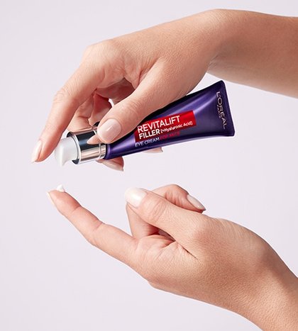 Eine Hand pumpt die Revitalift Filter Augencreme fuer das Gesicht aus ihrer Tube auf einen Finger