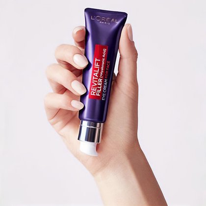 Eine Hand mit lackierten Naegeln haelt die Revitalift Filter Augencreme fuer das Gesicht