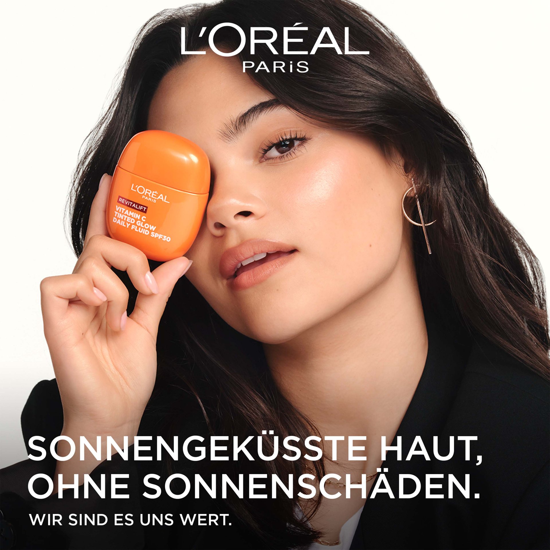 Eine Frau bedeckt ihr Auge spielerisch mit der orangefarbenen Revitalift-Flasche.
