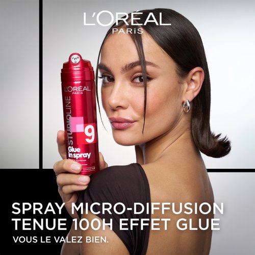 Eine Frau hält das rote Glue in Spray Haarspray in der Hand.