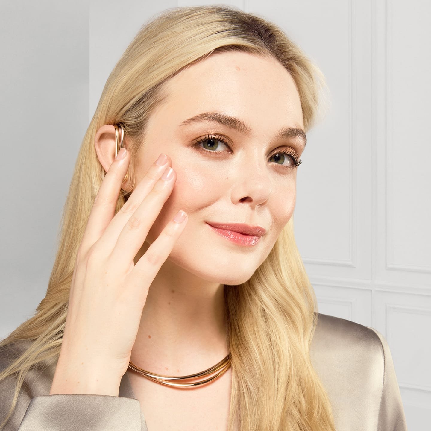 Eine junge Frau tastet mit ihrer Hand ihren Wangenbereich ab und lächelt dabei