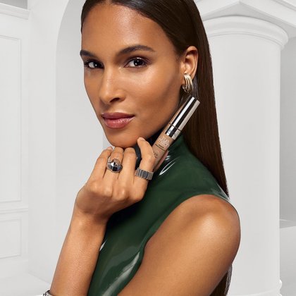 Eine junge Frau hält den Radiant Serum Concealer 9N Medium Deep in der Hand