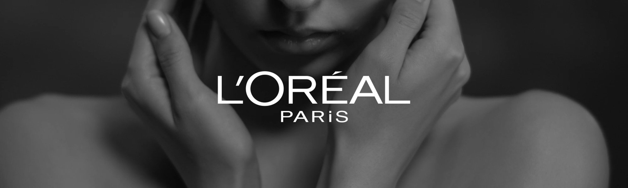 L'Oréal Paris Logo, im Hintergrund eine Frau, die ihre Hände an ihr Gesicht hält