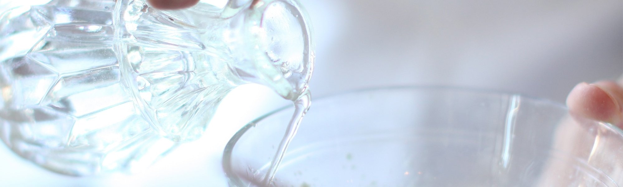 Thermalwasser wird aus einem kleinen Glaskännchen in eine Schüssel mit Pulver geschüttet