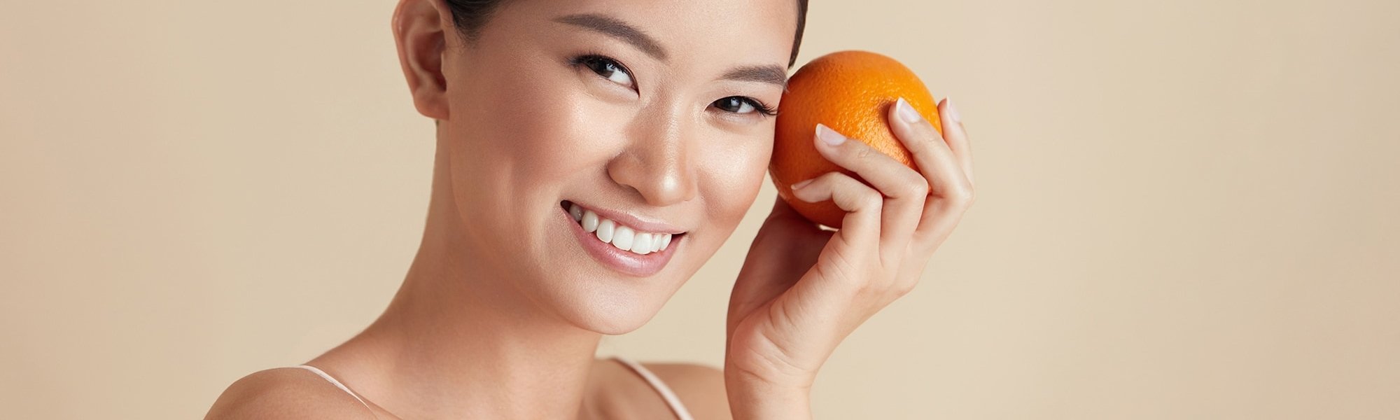 Eine Junge Frau hält sich eine Orange in der Hand