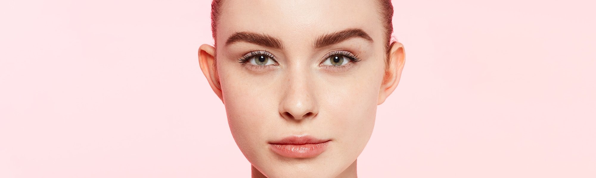 Junge Frau mit Augenbrauen Make-up vor rosa Wand
