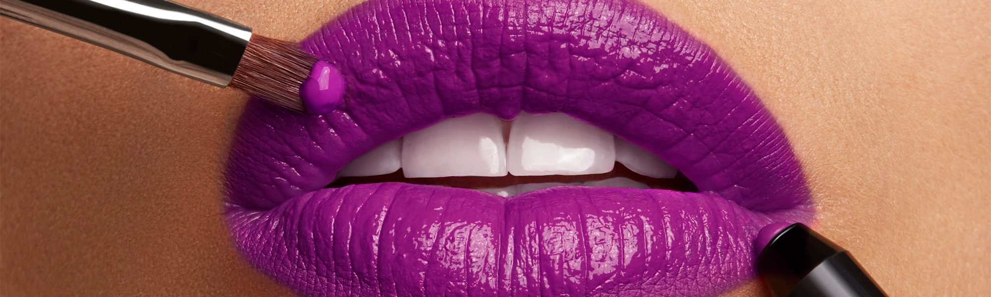 Volle Lippen werden mit Stift und Pinsel violett geschminkt