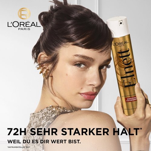 Eine junge Frau schaut über ihre Schulter und hält ein Elnett Haarspray in ihrer Hand